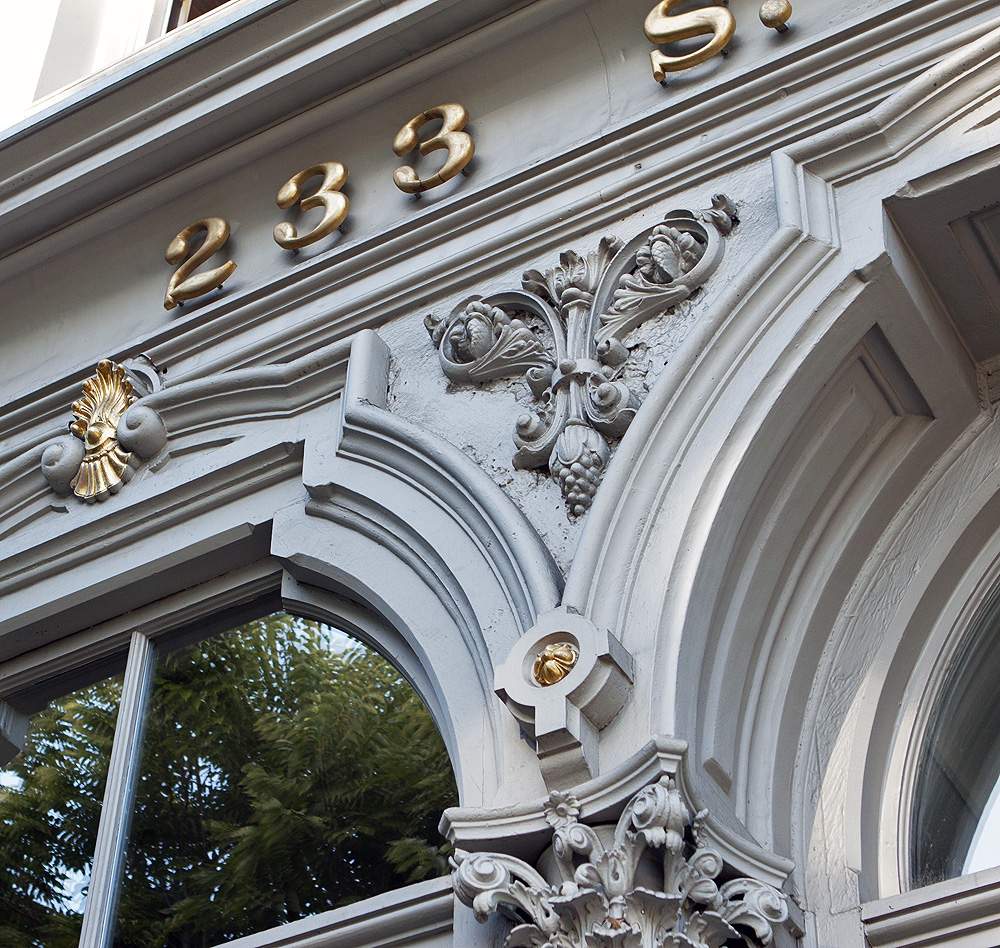 Cast iron facade detail. Look at the repeating reflections in the old glass.